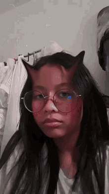 a young girl wearing glasses and devil horns on her head