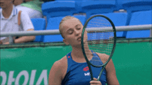 a woman holding a tennis racquet in front of a sign that says victor