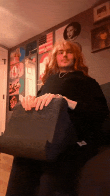 a man with red hair is sitting on a couch holding a box