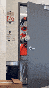 a mascot wearing a hat with the letter b on it is standing in a doorway