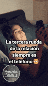 a man laying on a bed looking at his phone with a sad face on it