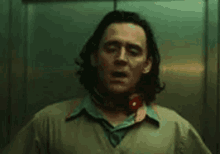 a man is standing in an elevator with his mouth open and a scarf around his neck .