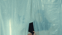a woman in a black hijab is behind a clear plastic curtain with the words allo written above her