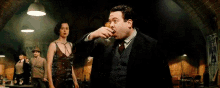 a man in a suit and tie is drinking from a glass
