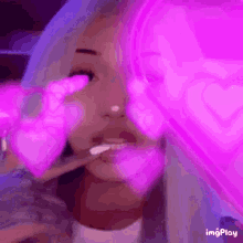 a woman with purple hair is holding a pink heart in her hand .