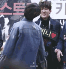 a man in a denim jacket is holding a sign that says ' i love you '