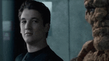 a young man in a black shirt is standing next to a statue of the thing .