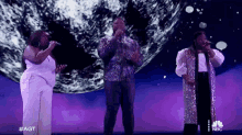 a group of people singing on a stage with nbc written on the bottom
