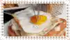 a close up of a fried egg on a sandwich with a fork sticking out of it .