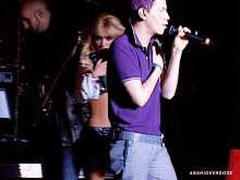 a man in a purple shirt sings into a microphone while a woman holds a microphone