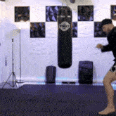 a man is kicking a tkc boxing bag in a gym