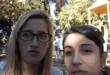 two women wearing glasses are standing next to each other in front of a playground