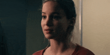 a young woman in a red shirt is looking at the camera .