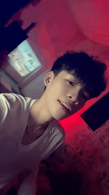 a young man taking a selfie in front of a red background