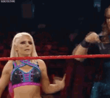 a female wrestler is standing in a wrestling ring with a man .
