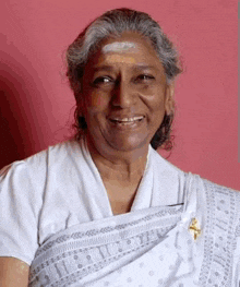 a woman wearing a white shirt and a gray shawl smiles for the camera