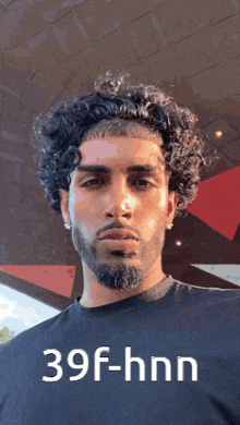 a man with curly hair and a beard is wearing a black shirt with 39f-hnn written on it