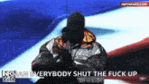 a man wearing a mask and a jacket with the words " everybody shut the fuck up "