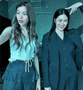 two women are standing next to each other and one is wearing a suit and smiling .