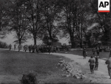 a black and white photo of soldiers walking down a road with ap written on the bottom right