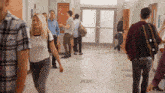 a group of people walking down a hallway in front of a sign that says brayen