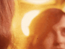 a close up of a woman 's face in a blurry photo with a yellow background .