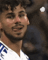 a man with a beard sticking his tongue out while wearing a blue and white jersey