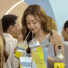 a woman is drinking through a straw from a cup that says lenamiu on it .