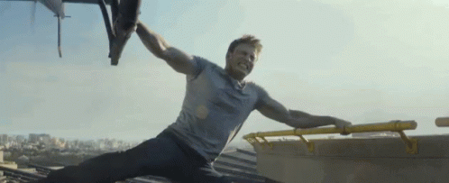 a man in a grey shirt is laying on the ground with his arms outstretched .
