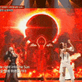 two women singing on a stage with the words " the night into the sun " on the bottom right