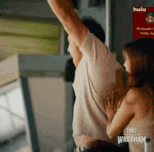 a man and a woman are hugging each other in front of a sign that says wrexham .