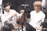 two men are sitting in front of a microphone and a laptop