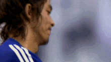 a man with long hair wearing a blue adidas jersey