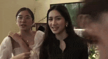 a group of women are standing next to each other in a room and talking to each other .