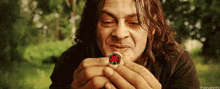 a man with long hair is holding a coin in his hands with a red circle on it