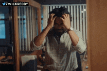 a man with his hands on his head with a 7wickreddy logo in the background