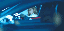 a woman is sitting in a car with a man behind her