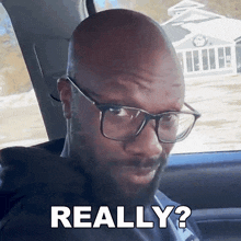 a man wearing glasses and a beard is making a really face