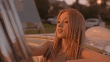 a woman with blonde hair is sitting in a white car