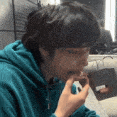 a young man wearing a blue hoodie is eating something .