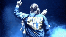 a man wearing a blue jacket that says sdtm2 on the back