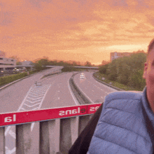 a man stands on a bridge overlooking a highway with a sign that says en6l9