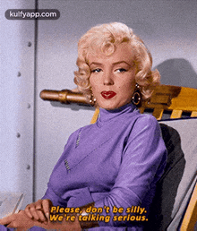 a woman in a purple dress is sitting in a chair and saying please don 't be silly .