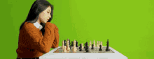 a woman is playing chess on a green screen