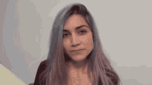 a woman with purple hair is making a funny face and looking at the camera .