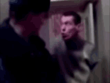 a blurry picture of a man talking to another man in a room .