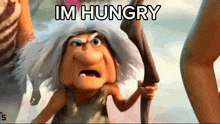a cartoon character from the movie croods is holding a stick and says im hungry .