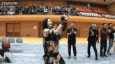a woman in a wrestling outfit stands in front of a crowd and a sign that says stardom on it