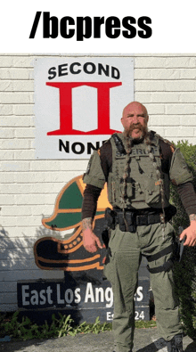 a man with a beard stands in front of a sign that says second ii non