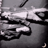 a black and white photo of two people laying on their backs with a crescent moon in the foreground